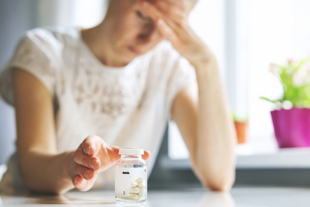 Side Effects of Benzos a woman examines a pill bottle and considers the side effects of benzos
